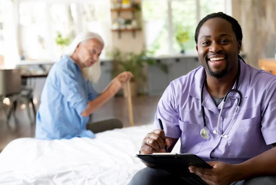Male nurse in scrubs with stethoscope checking vitals of an older woman